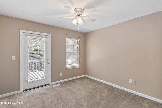 spare room featuring visible vents, light carpet, ceiling fan, a textured ceiling, and baseboards