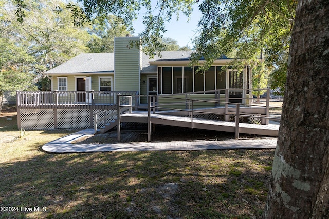 back of house with a wooden deck, a sunroom, and a lawn