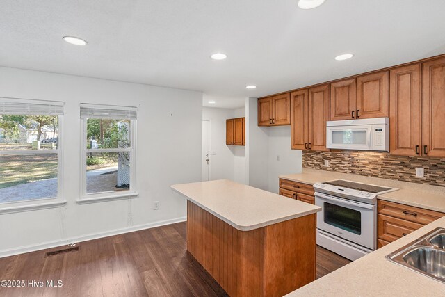 kitchen featuring sink, white appliances, tasteful backsplash, a kitchen island, and dark hardwood / wood-style flooring