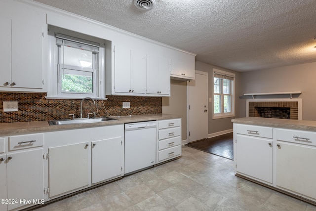 kitchen with dishwasher, white cabinets, sink, a fireplace, and a textured ceiling