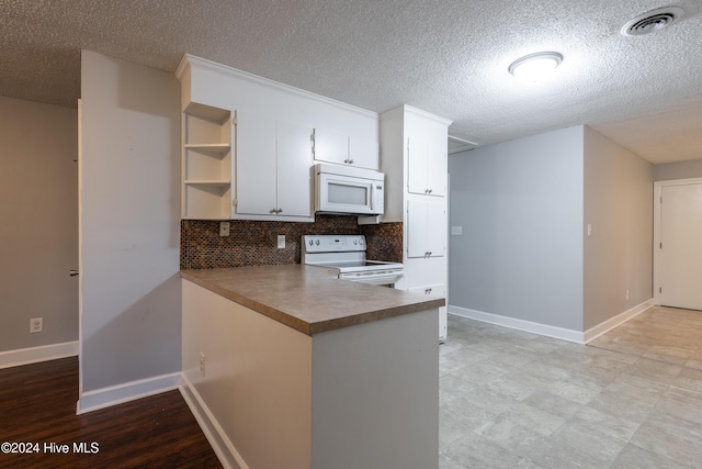 kitchen featuring kitchen peninsula, backsplash, a textured ceiling, white appliances, and white cabinetry