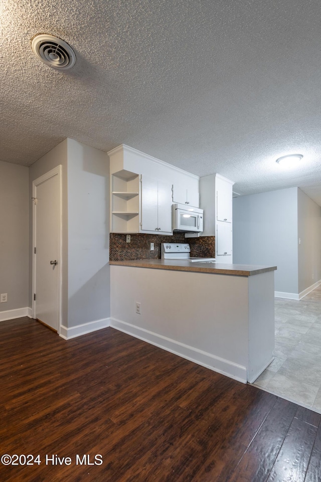 kitchen with white cabinetry, dark hardwood / wood-style flooring, backsplash, kitchen peninsula, and white appliances