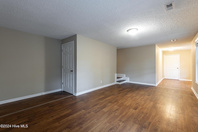 empty room featuring dark wood-type flooring and a textured ceiling