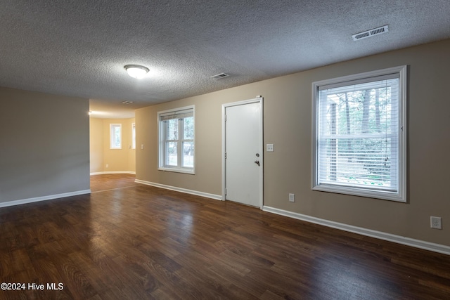 unfurnished room featuring a textured ceiling and dark hardwood / wood-style floors