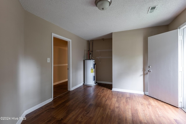 interior space featuring dark hardwood / wood-style flooring, electric water heater, and a textured ceiling