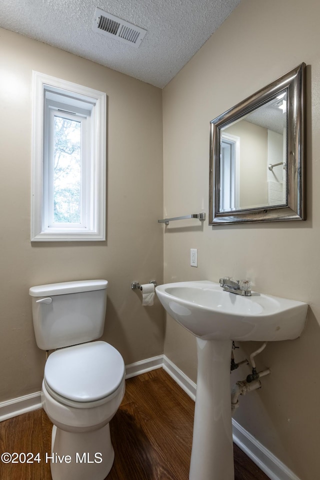 bathroom featuring hardwood / wood-style flooring, toilet, and a textured ceiling