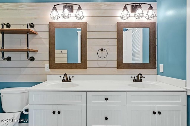 bathroom with vanity, toilet, and wooden walls