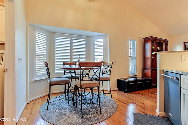 dining area featuring high vaulted ceiling and light wood-type flooring