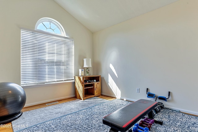 workout area featuring lofted ceiling and light hardwood / wood-style flooring