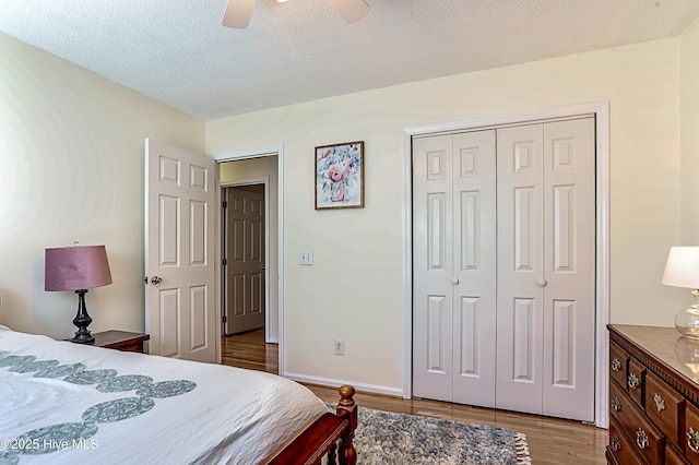 bedroom featuring ceiling fan, light hardwood / wood-style flooring, a closet, and a textured ceiling