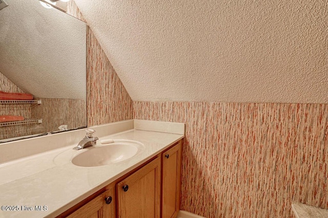 bathroom featuring vanity, vaulted ceiling, and a textured ceiling