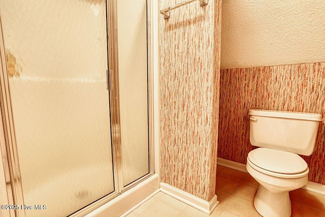 bathroom with toilet, a shower with shower door, and tile patterned flooring