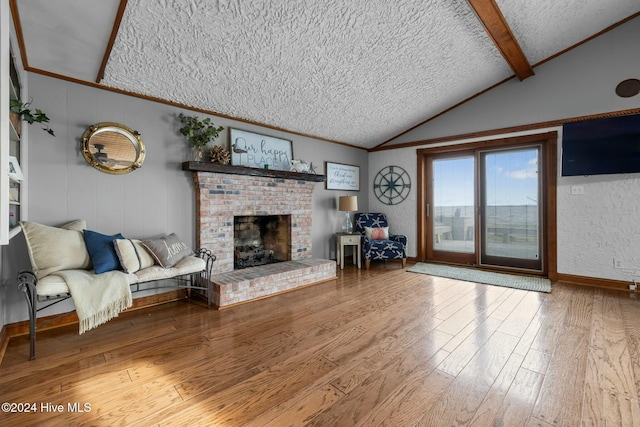 living room with wood-type flooring, a brick fireplace, a textured ceiling, and lofted ceiling with beams