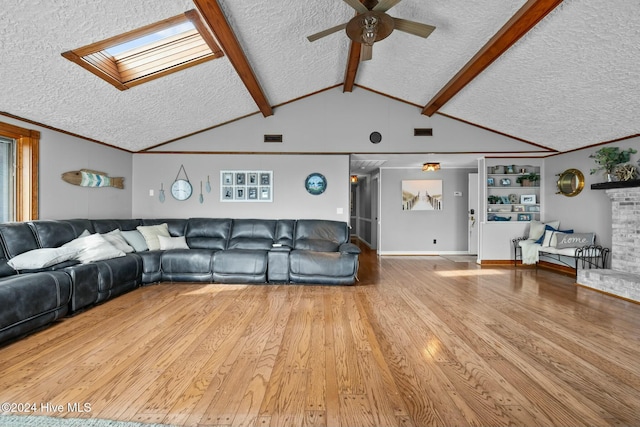 unfurnished living room featuring lofted ceiling with skylight, a textured ceiling, ceiling fan, and light wood-type flooring