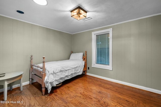 bedroom with ornamental molding and wood-type flooring