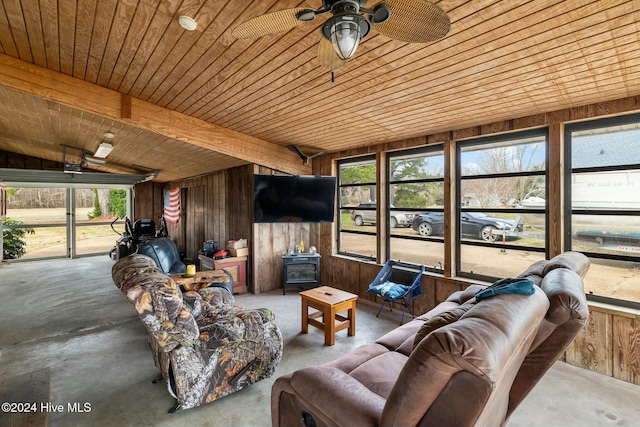 sunroom featuring wood ceiling, ceiling fan, a wood stove, and plenty of natural light