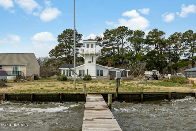 view of dock featuring a balcony, a lawn, and a water view