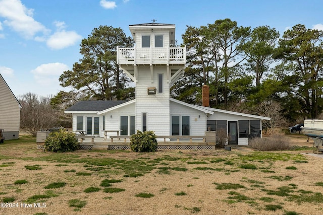 back of house featuring a balcony, a yard, and a sunroom