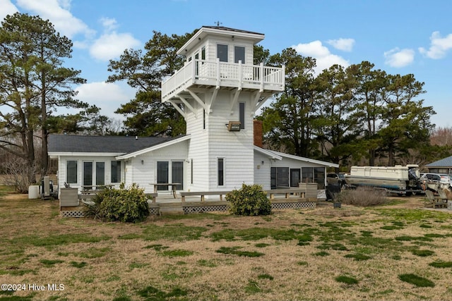 rear view of property featuring a deck and a lawn