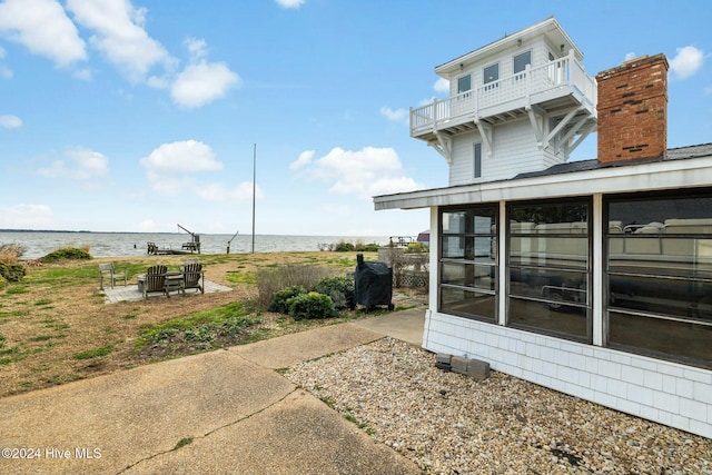 view of yard featuring a balcony, a sunroom, and a water view