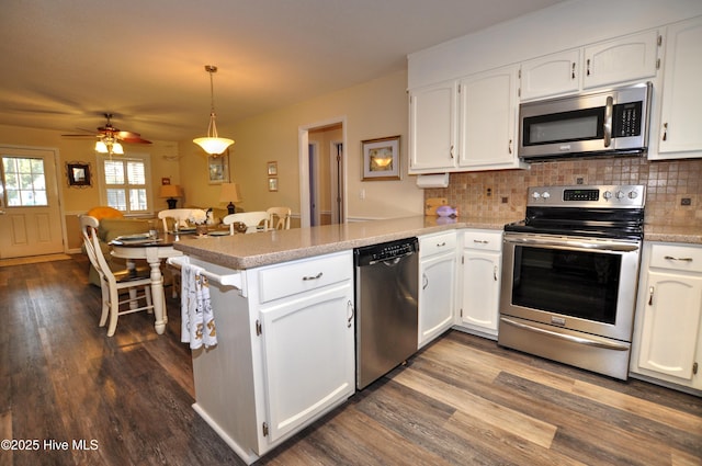 kitchen with white cabinetry, appliances with stainless steel finishes, kitchen peninsula, and hanging light fixtures