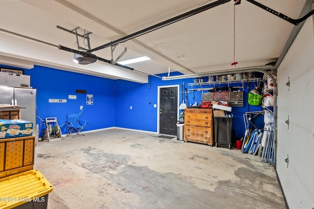 garage with stainless steel fridge and a garage door opener