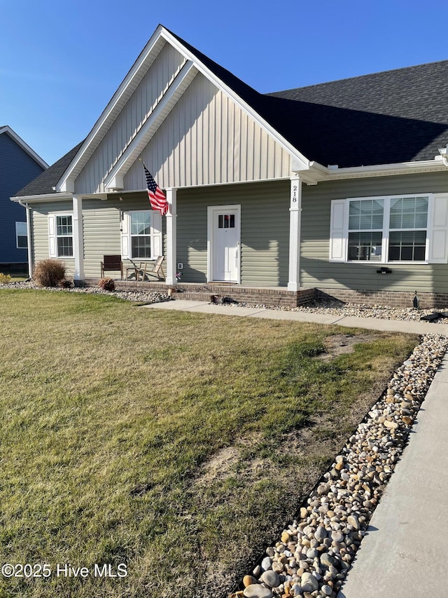 view of front of property with roof with shingles, a front lawn, and board and batten siding