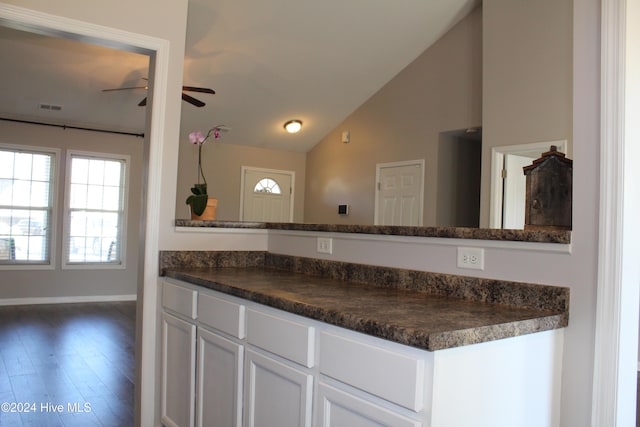 kitchen featuring white cabinetry, ceiling fan, dark hardwood / wood-style flooring, dark stone countertops, and lofted ceiling