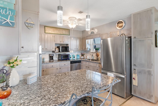 kitchen with ceiling fan, sink, stainless steel appliances, and a textured ceiling