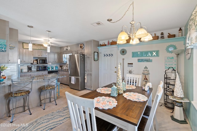 dining space featuring ceiling fan with notable chandelier