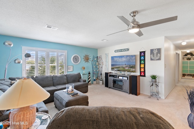 living room featuring a textured ceiling, light colored carpet, and ceiling fan