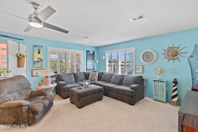 living room featuring light carpet, ceiling fan, and a textured ceiling