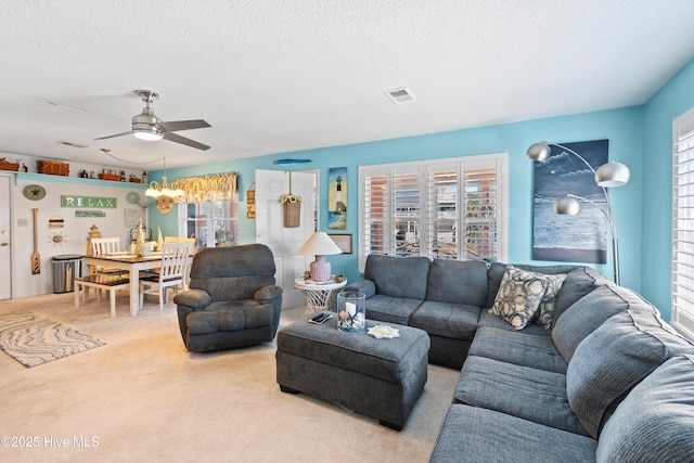 living room with a textured ceiling, light colored carpet, and ceiling fan