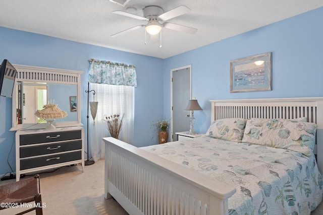 carpeted bedroom featuring ceiling fan and a textured ceiling