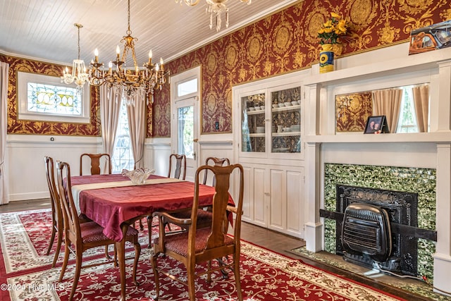 dining space featuring a tile fireplace, plenty of natural light, dark hardwood / wood-style floors, and an inviting chandelier