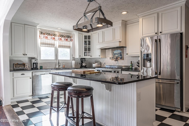 kitchen with white cabinets, a textured ceiling, stainless steel appliances, and a kitchen island