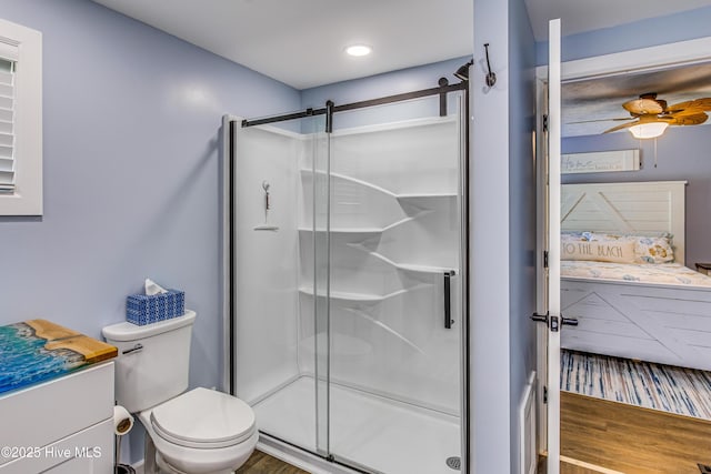 bathroom featuring vanity, wood-type flooring, ceiling fan, toilet, and a shower with shower door