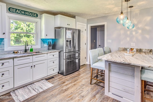 kitchen featuring white cabinets, stainless steel fridge, tasteful backsplash, and sink