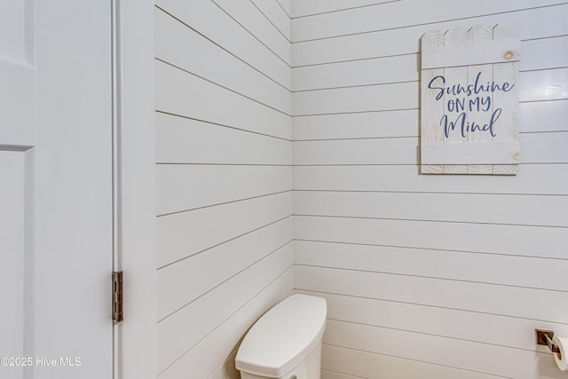 bathroom with wood walls and toilet