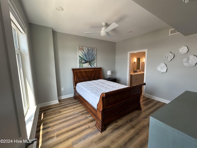 bedroom with ceiling fan, ensuite bathroom, dark hardwood / wood-style flooring, and multiple windows