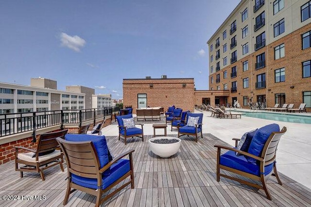 wooden terrace featuring outdoor lounge area, a community pool, and a patio area