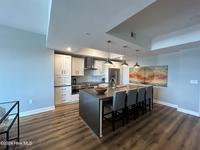 kitchen with white cabinetry, wall chimney exhaust hood, a tray ceiling, and pendant lighting