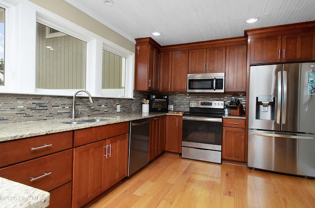 kitchen with light stone counters, light hardwood / wood-style flooring, decorative backsplash, appliances with stainless steel finishes, and sink