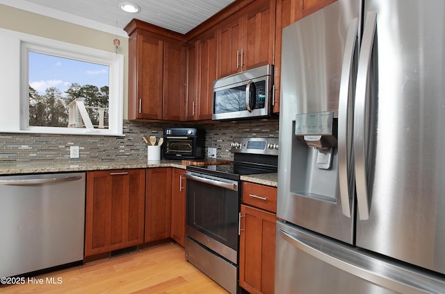 kitchen featuring appliances with stainless steel finishes, light hardwood / wood-style floors, light stone counters, and decorative backsplash