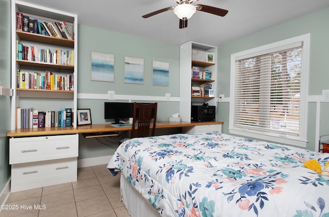 tiled bedroom featuring built in desk, ceiling fan, and multiple windows