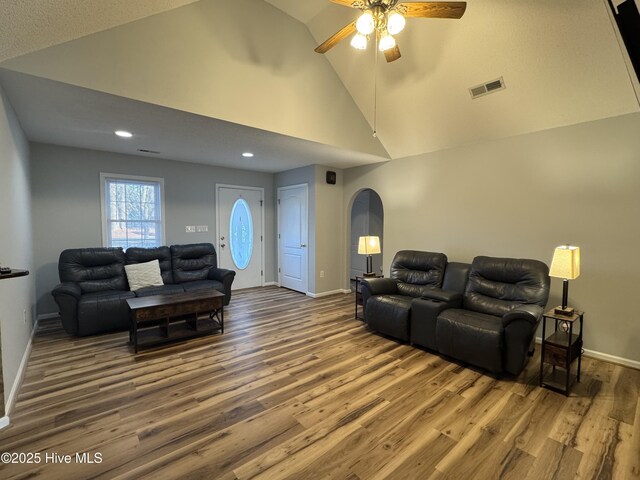 living room featuring lofted ceiling, a textured ceiling, ceiling fan, a tiled fireplace, and hardwood / wood-style floors