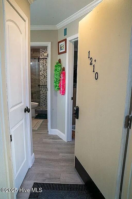 corridor with hardwood / wood-style floors and ornamental molding