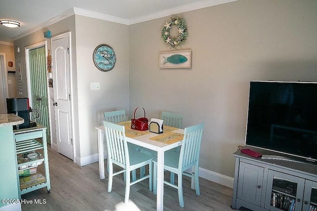 dining area with light wood-type flooring and crown molding