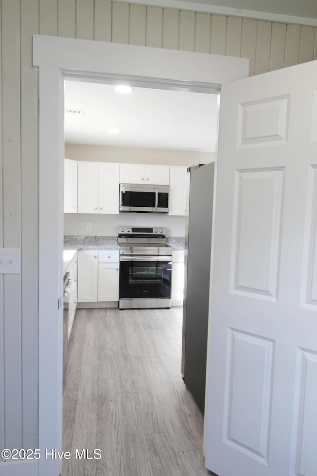 kitchen with light hardwood / wood-style floors, white cabinetry, and stainless steel appliances