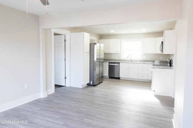 kitchen featuring white cabinets, light wood-type flooring, stainless steel appliances, and sink